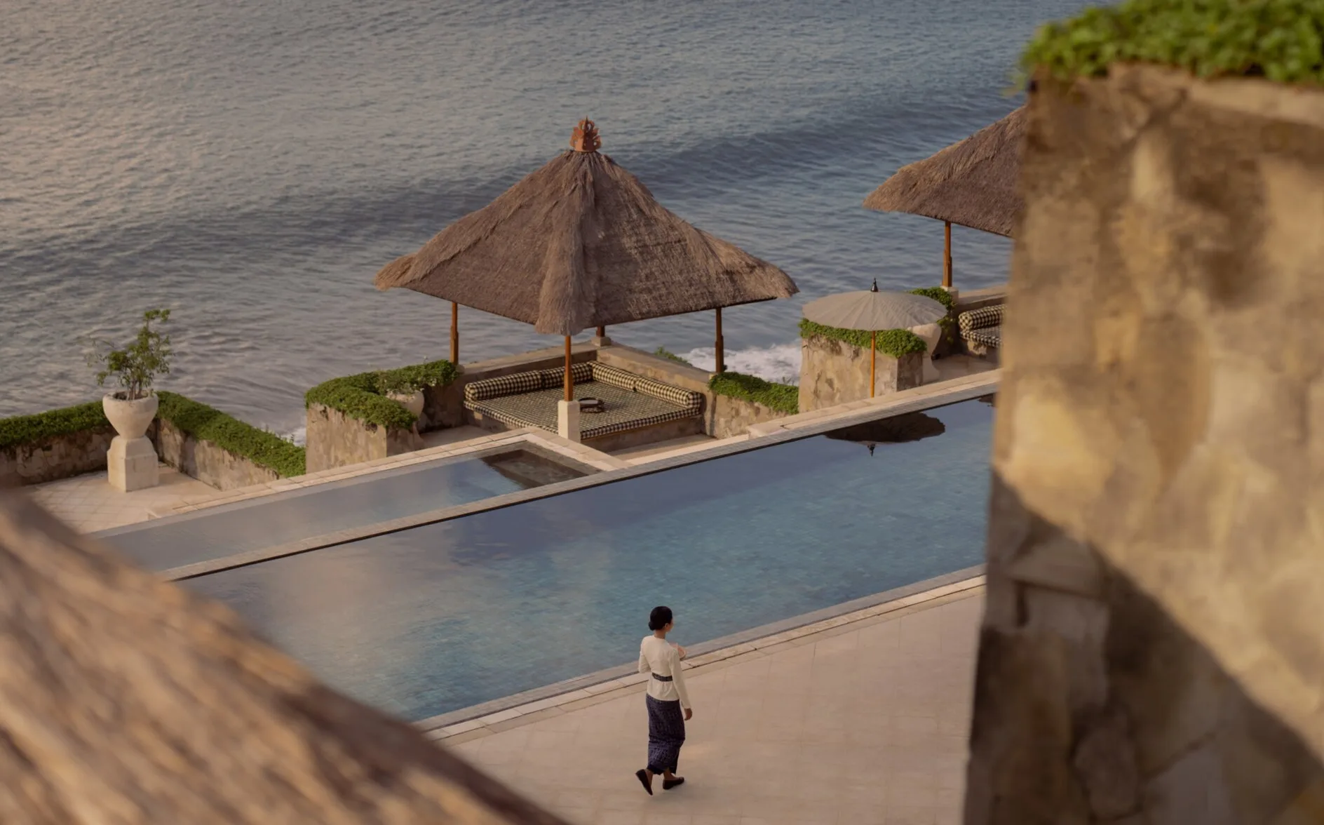 Clifftop pool overlooking the ocean at Amankila, Indonesia, with traditional wooden pavilion and stone terracing.