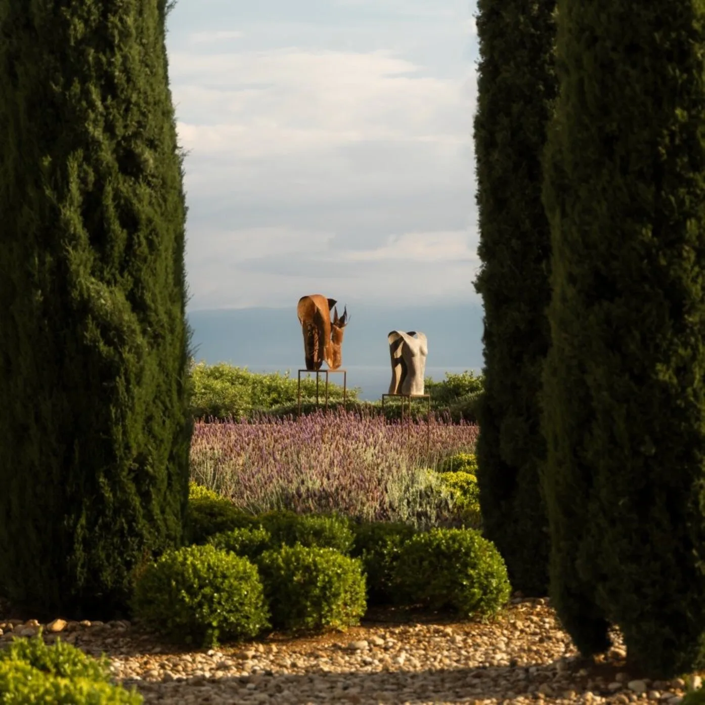 Figures walking through lavender fields at Amanzoe, Greece, framed by cypress trees.