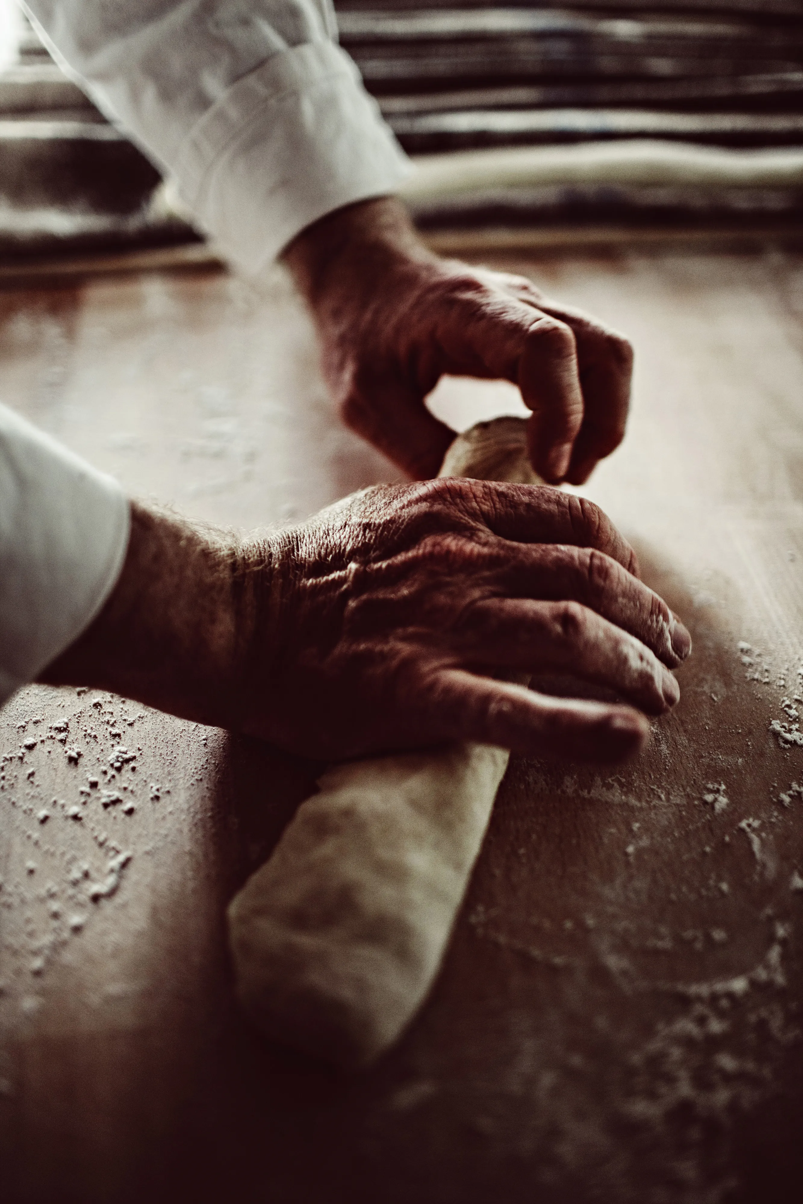 Un boulanger façonne à la main une pâte à pain sur un plan de travail fariné, geste emblématique du savoir-faire traditionnel.