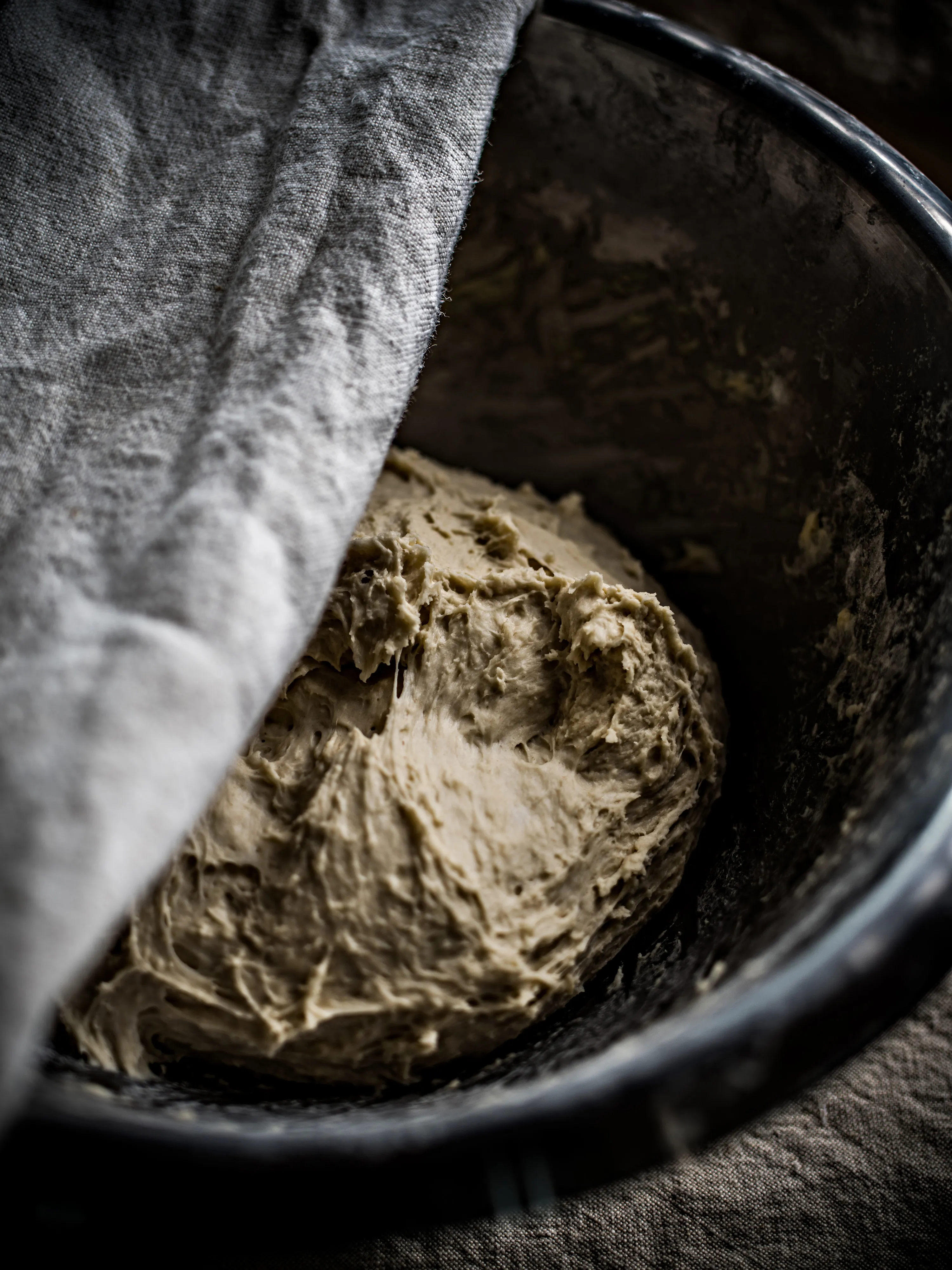 Pâte à pain reposant sous un linge de lin dans un cul-de-poule, préparée pour la phase de pousse dans le cadre d’une fabrication artisanale.