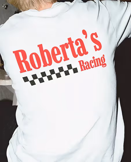 Person wearing a white shirt with red text 'Roberta's Racing' and a black and white checkered racing pattern on the back.